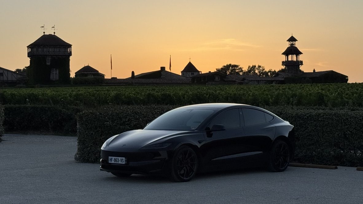 Tesla Model 3 noire au coucher du soleil devant Les Sources de Caudalie, Martillac