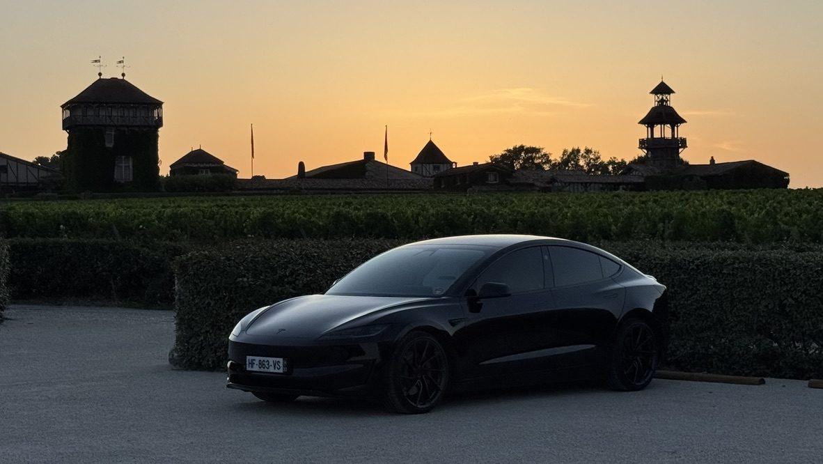 Tesla Model 3 noire au coucher du soleil devant Les Sources de Caudalie, Martillac